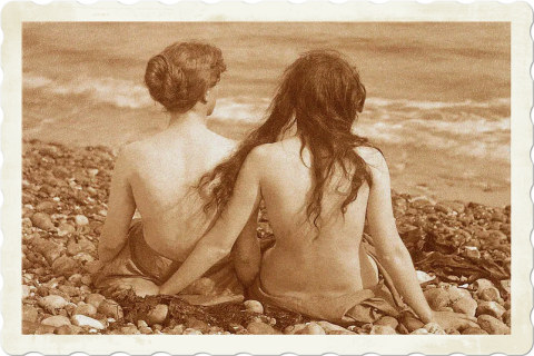 an old photograph of two women sitting on a beach